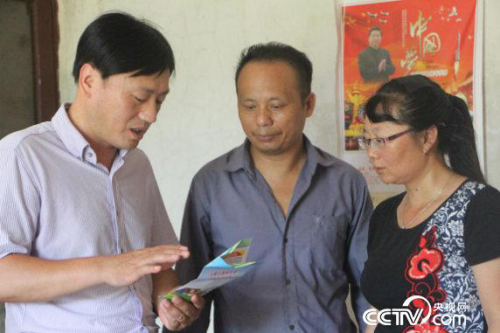 Lan Jianfeng, deputy director of the Aiwei Association of Yudu County Health Planning Commission, is patiently explaining the "five security lines" policy to villager Duan Shaoping.